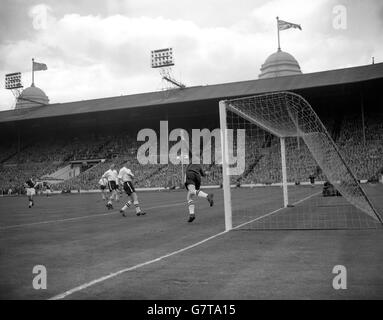 Le gardien de but de Luton Town Ron Baynham saute pour le ballon, mais il l'échappe et entre dans le filet pour le deuxième but de Nottingham Forest - marqué par le centre-avant Tommy Wilson (extrême gauche) - dans la finale de la coupe FA à Wembley. Les joueurs de Luton regardent avec beaucoup leur capitaine, Syd Owen (troisième à partir de la droite). Banque D'Images