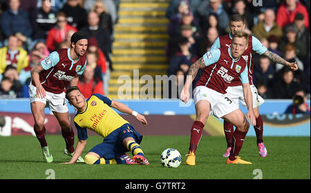 Mesut Ozil d'Arsenal lutte pour le ballon avec George Boyd (à gauche) de Burnley et Scott Arfield lors du match de la Barclays Premier League à Turf Moor, Burnley. Banque D'Images