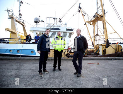 Le chef libéral démocrate Nick Clegg (à gauche), le maître de port Rob Parsons (au centre) et le candidat local Andrew George regardent les chalutiers de pêche amarrés dans le port lors d'une visite au marché aux poissons de Newlyn à Cornwall. Banque D'Images