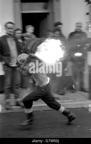 Cérémonie de brûlage du baril de goudron - l'Ottery St Mary's.Un garçon court dans la rue avec un tonneau en feu pendant l'événement des écoliers. Banque D'Images