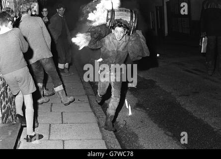 Cérémonie de brûlage du baril de goudron - l'Ottery St Mary's.Un garçon porte un baril dans la rue. Banque D'Images
