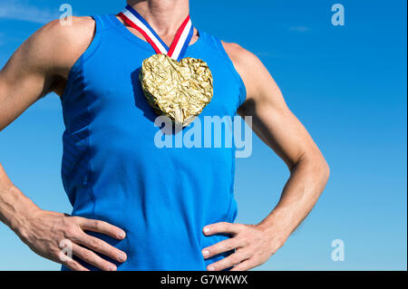 Comité permanent de l'athlète américain avec médaille d'or en forme de cœur suspendu à rouge, blanc et Blue Ribbon against blue sky Banque D'Images