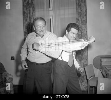 Malgré ses 67 ans, le muscleman du film Victor McLaglan (l) montre au jeune homme, l'ancien champion du monde de boxe léger Freddie Mills, qu'il est toujours aussi dur que le meilleur d'entre eux.Freddie, aujourd'hui promoteur de la boxe, a visité McLaglan à l'hôtel Savoy de Londres et l'a mis au défi d'un 'dell' avec un expandeur de poitrine. Banque D'Images