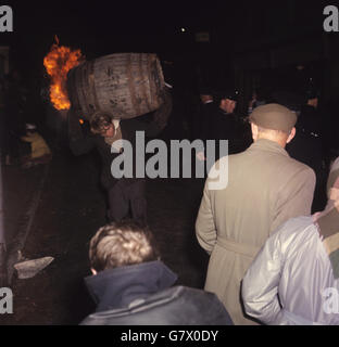 Un homme traverse la rue et porte un baril en feu. Banque D'Images