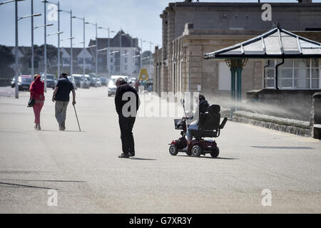 Les gens sont blamés par le sable car il souffle sur la plage de Weston-super-Mare lors d'une journée chaude et venteuse sur la côte du Canal de Bristol dans le Somerset. Banque D'Images