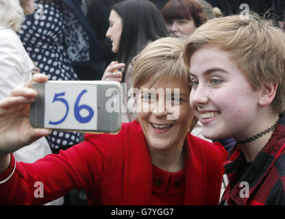 Le premier ministre d'Écosse Nicola Sturgeon prend un selfie avec un SNP après une photo avec des députés nouvellement élus du SNP devant le Forth Rail Bridge dans le sud du Queensferry alors que le parti marque sa victoire électorale générale historique en Écosse. Banque D'Images