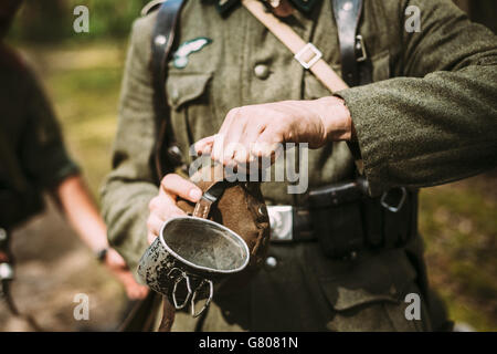 La reconstitution médiévale non identifiés habillés en soldat allemand pendant la Seconde Guerre mondiale ouvre la fiole avec de l'eau. Banque D'Images