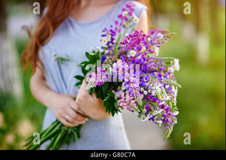 Femme tenant un bouquet de fleurs de lupin bleu Banque D'Images