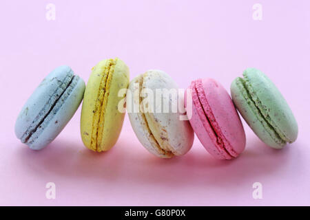 Biscuits aux amandes macarons multicolores français sur un fond rose Banque D'Images