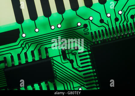 Concept de technologie informatique. Carte de circuit imprimé / carte de circuit imprimé montrant les composants rétroéclairés avec un voyant vert. Câblage à l'intérieur du calculateur, gros plan du circuit, électronique Banque D'Images