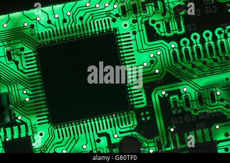 Concept de technologie informatique. Carte de circuit imprimé / carte de circuit imprimé montrant les composants rétroéclairés avec un voyant vert. Câblage à l'intérieur du calculateur, gros plan du circuit, électronique Banque D'Images
