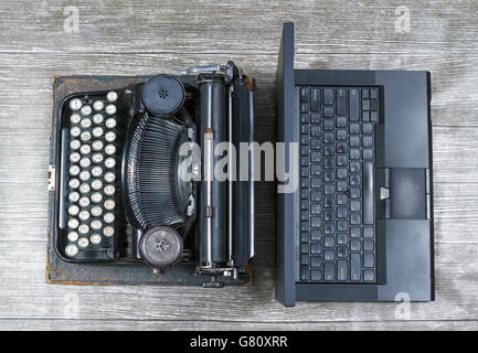 Vieille machine à écrire sur un fond gris texturé le long d'un ordinateur portable moderne noir Banque D'Images