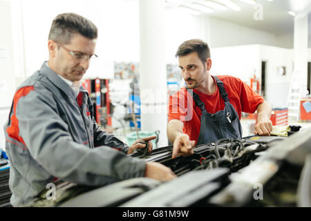 Fixation mécanique auto voiture dans garage - travail d'équipe Banque D'Images