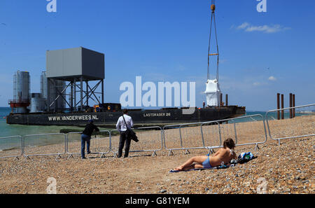 Les gens regardent comme des composants qui formeront le i360 à Brighton, dans l'est du Sussex, la première tour d'observation verticale de téléphérique au monde, sont déchargés sur Brighton Beach avant les travaux de construction. Banque D'Images