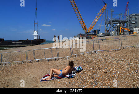 Une dame montre, en tant que composants qui formeront le i360 à Brighton, dans l'est du Sussex, la première tour verticale d'observation de téléphérique au monde, sont déchargés sur Brighton Beach avant les travaux de construction. Banque D'Images