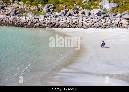 Deux personnes sur plage déserte, l'aigue-marine bleu de la mer avec les îles Lofoten, Norvège arctique boulders Banque D'Images