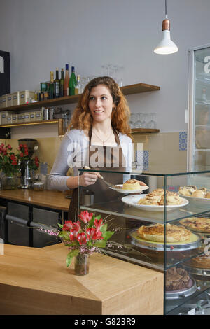 Jeune femme cannelle tout en se tenant au café Banque D'Images
