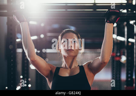 Close-up of young woman doing chin-ups at gym Banque D'Images