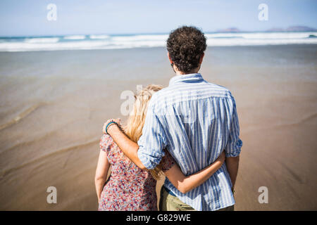 Vue arrière du couple aimant autour du bras de commandes at beach Banque D'Images