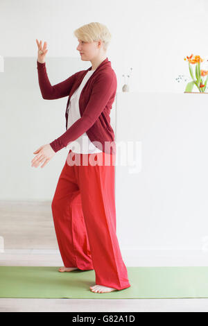 Vue latérale sur toute la longueur de la fit woman exercising on yoga mat à la maison Banque D'Images