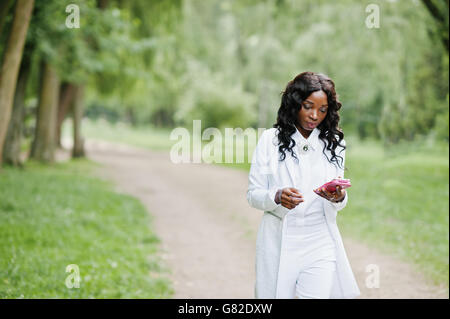 Noir élégant african american girl walking on park avec un téléphone mobile à portée de main Banque D'Images