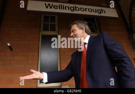 Le Premier ministre britannique Tony Blair lance son téléphone portable à un assistant, en attendant un train à la gare de Wellingborough. Banque D'Images