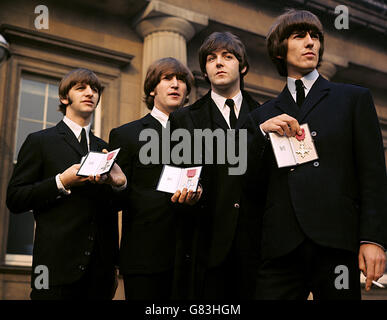 Les Beatles montrant leurs insignes MBE dans la piste après les avoir reçus de la Reine. (l-r) Ringo Starr, John Lennon, Paul McCartney et George Harrison. Banque D'Images