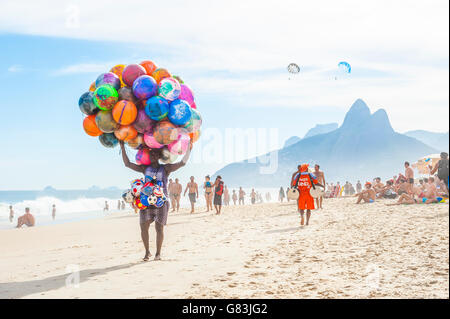 RIO DE JANEIRO - le 20 janvier 2013 : : Plage vendeur vente de ballons de plage coloré porte ses marchandises le long de la plage d'Ipanema. Banque D'Images