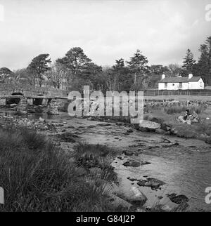 Des groupes de randonneurs déjeunent au bord de la rivière East Dart, près de l'ancien pont clapper à Postbridge, Dartmoor. Banque D'Images