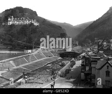 Au premier plan, un pont temporaire traverse l'East Lyn tandis que les ouvriers continuent de construire l'un des deux nouveaux ponts à Lynmouth. Il y a trois ans, les eaux alimentaires faisaient rage dans le petit village de Devon, balayant 32 000 personnes à mort. Banque D'Images