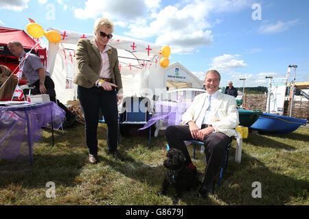 Nigel Farage, le leader du UKIP, pose une photo tandis que l'eurodéputée locale Jane Collins demande à son chien Harry de s'asseoir et d'attendre pendant qu'il visite le salon CLA Gamefair (association des propriétaires fonciers de pays) à Harewood House, près de Leeds , West Yorkshire. Banque D'Images