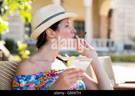 Une femme dégustant un cocktail et un cigare dans un hôtel à La Havane, Cuba Banque D'Images