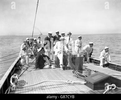 Le roi George V à bord de son yacht « Britannia » tandis que le navire royal naviguait avec le vent pendant la course à Cowes.Le major Hunloke, le skipper, est vu à la roue du yacht royal. Banque D'Images