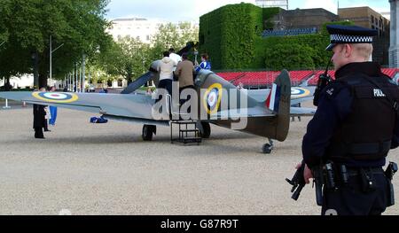 Un policier armé regarde les visiteurs grimper sur une réplique de 1939 Chasseur de Spitfire dans la parade des gardes à cheval de Londres Banque D'Images