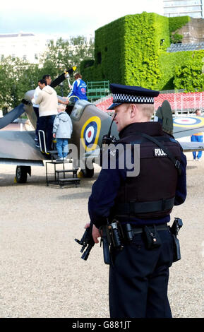 Un policier armé regarde les visiteurs monter sur une réplique 1939 de Spitfire dans Horse Guards Parade. L'avion sera utilisé pour les célébrations entourant le 60e anniversaire de la journée du VE et les événements entourant la candidature olympique de Londres 2012. Banque D'Images