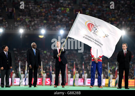 Lynn Davies, présidente de l'athlétisme britannique, tire le drapeau de l'IAAF en tant que présidente sortante de l'IAAF, Lamine Diack (deuxième à gauche), regarde pendant la neuvième journée des championnats du monde de l'IAAF au stade national de Beijing, en Chine. Banque D'Images