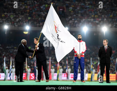 La présidente sortante de l'IAAF, Lamine Diack, remet le drapeau de l'IAAF à la présidente britannique de l'athlétisme, Lynn Davies (à droite), au cours du neuvième jour des Championnats du monde de l'IAAF au stade national de Beijing, en Chine. Banque D'Images