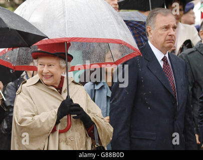 La reine Elizabeth II est sous un parapluie alors qu'elle marche aux côtés du premier ministre canadien Paul Martin, à l'édifice de l'Assemblée législative de Regina, en Saskatchewan, le deuxième jour de sa visite au pays. Banque D'Images