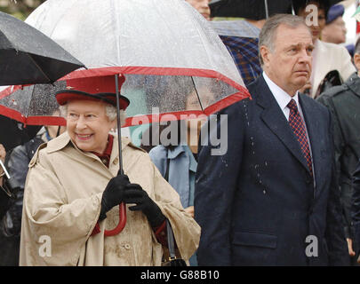 La reine Elizabeth II est sous un parapluie alors qu'elle marche aux côtés du premier ministre canadien Paul Martin, à l'édifice de l'Assemblée législative de Regina, en Saskatchewan, le deuxième jour de sa visite au pays. Banque D'Images