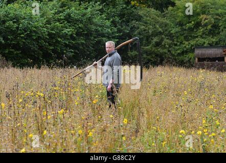 Tom Normandale, chargé de projet de Cornfield Flowers, porte sa scythe avant de récolter la taille haute de graines de fleurs sauvages rares au Ryedale Folk Museum, Hutton le Hole, North Yorkshire. Banque D'Images