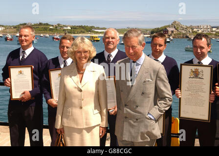 Le prince de Galles et la duchesse de Cornwall présentent des certificats aux membres de RNLI sur le mur du port. Banque D'Images