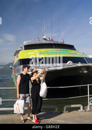 Un couple chinois se prépare à prendre un bateau de tourisme à la grande barrière de corail, Cairns, Queensland, Australie. Banque D'Images