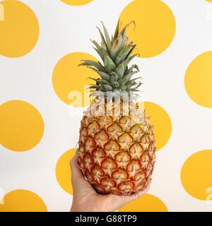 Woman holding pineapple en face de tache jaune background Banque D'Images