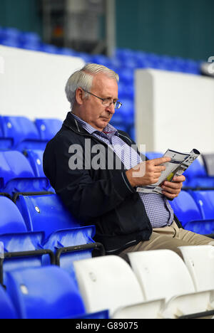 Un fan lit le programme d'allumette dans les stands avant le début du match. Banque D'Images