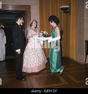 La reine Elizabeth la reine mère reçoit un bouquet d'Elspeth Earle, présidente du comité sportif de l'Université des femmes, lorsqu'elle a assisté au dîner et au bal du président de l'Union au Sénat de l'Université de Londres.Le président de l'Union, M. Drummond D. A. Leslie, est photographié à gauche. Banque D'Images