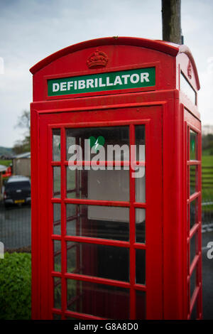 Une boîte de téléphone rouge vif convertie en chambre d'urgence et défibrillateur en cas de crises cardiaques , sur le bord de la route en Cwrt village, Parc National de Snowdonia, Gwynedd, au nord du Pays de Galles UK Banque D'Images