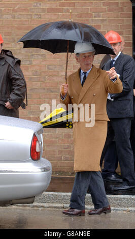 Le Prince de Galles sous un parapluie lorsqu'il visite Poundbury, pour présenter la 100e maison construite dans son village modèle de Dorset par le Guinness Trust. Banque D'Images