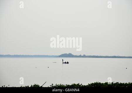 Silhouette de pêcheur La pêche en bateau en bois dans le lac Nong Han dans Amphoe Kae, Thaïlande Banque D'Images