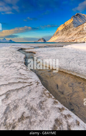 Le golden sunrise compte dans un ruisseau clair de la mer où la neige a fondu haukland lofoten, Norvège europe Banque D'Images