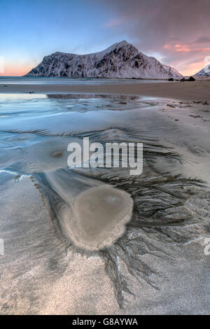 Coucher du soleil sur le surréel skagsanden plage entourée de montagnes couvertes de neige flakstad lofoten, Norvège du nord de l'Europe Banque D'Images